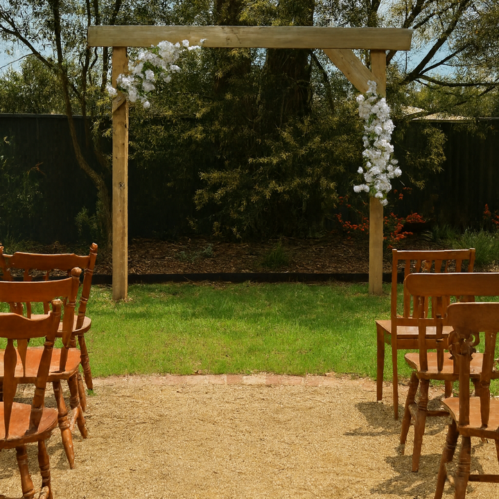 2pc garland attached to wooden arbor in front of garden with wooden chairs