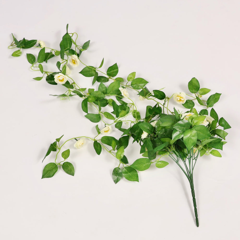 Artificial green vine bouquet with small white flowers on a light gray background
