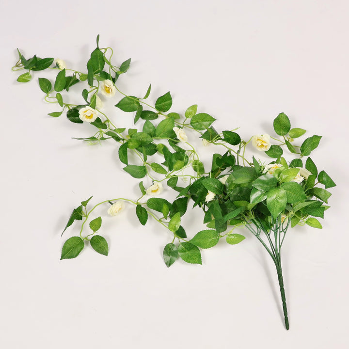 Artificial green vine bouquet with small white flowers on a light gray background