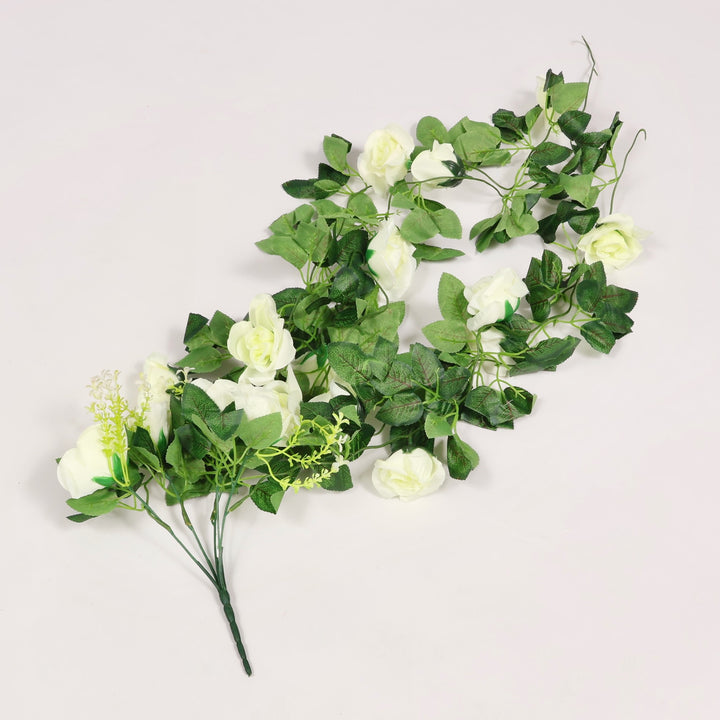 Artificial green leaves and white flowers bouquet on a light gray background
