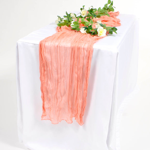 CORAL COLOURED CHEESECLOTH TABLE RUNNER ON WHITE TABLECLOTH WITH WHITE ROSE VINE WITH GREEN LEAVES