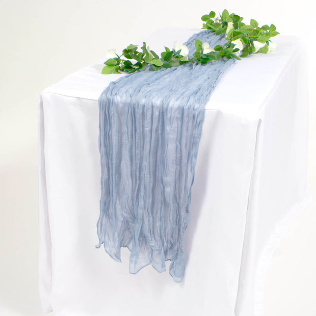 Light blue cheesecloth runner on white tablecloth with white rose vine