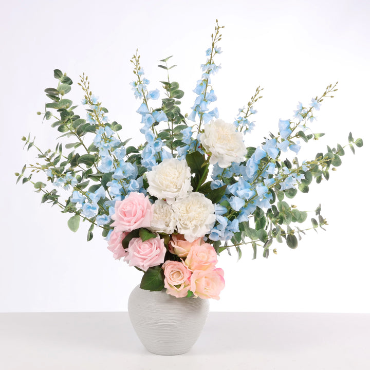 Mixed flower arrangement containing Light Blue Foxgloves, Pink Blossomed Roses, White Peony Roses, Eucalyptus and Peach Peony stems displayed in the Textured Centrepiece Urn Shaped Vase - Light Grey (18x23cm)