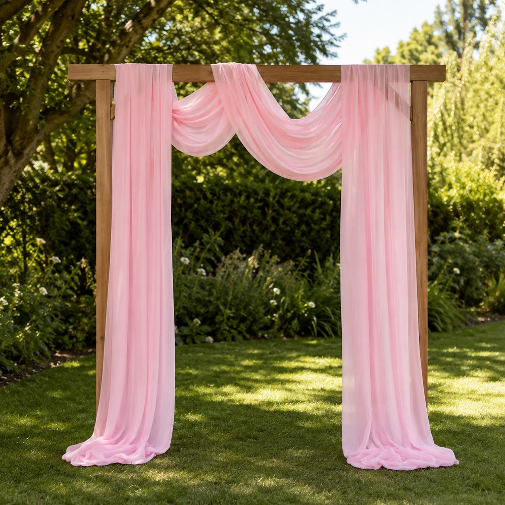 Light pink chiffon draped over a wooden arbor in a garden