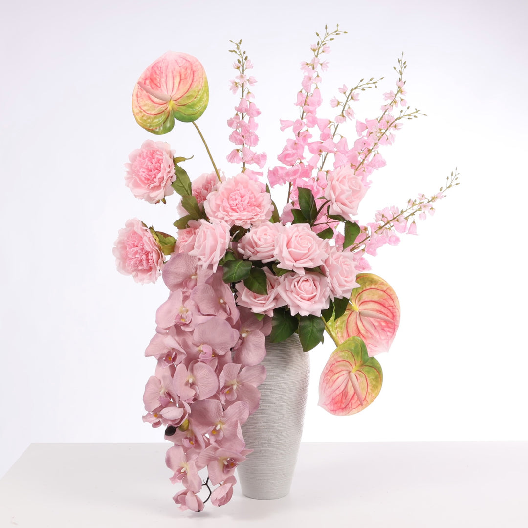Pink flower arrangement made up of Orchids, Peony Roses, Anthurium, Roses and Foxglove stems displayed in Textured Centrepiece Urn Shaped Vase - Light Grey (18x34cm)