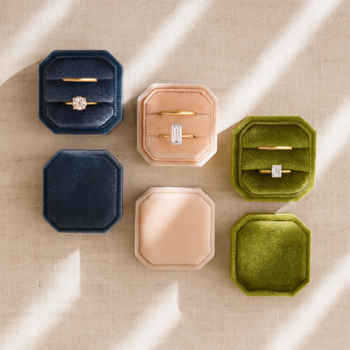 Flat lay image of velvet ring boxes - olive, ivory and dusty blue with rings inside
