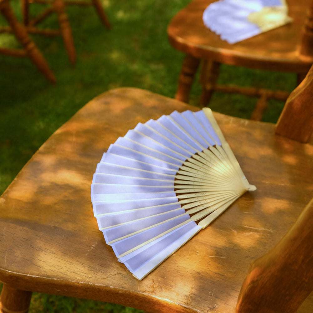 Silk hand fan sitting on a wooden chair in the sunshine
