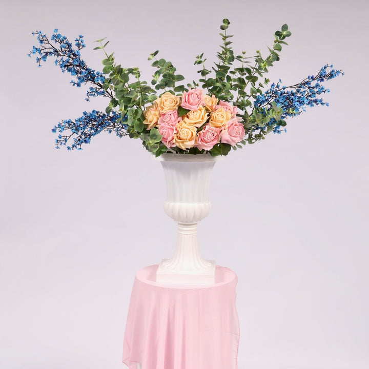 Trumpet vase on plinth with blue cherry blossom, eucalyptus stems and roses in peach and light pink. 