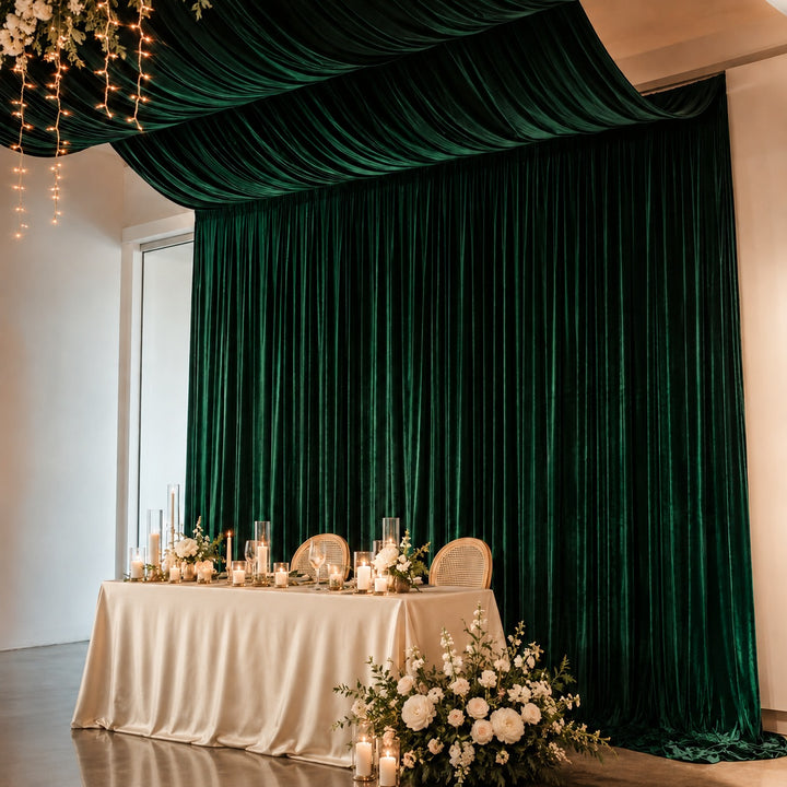 Emerald green velvet backdrop used behind bridal table, also suspended from roof as ceiling draping to create one cohesive looking display
