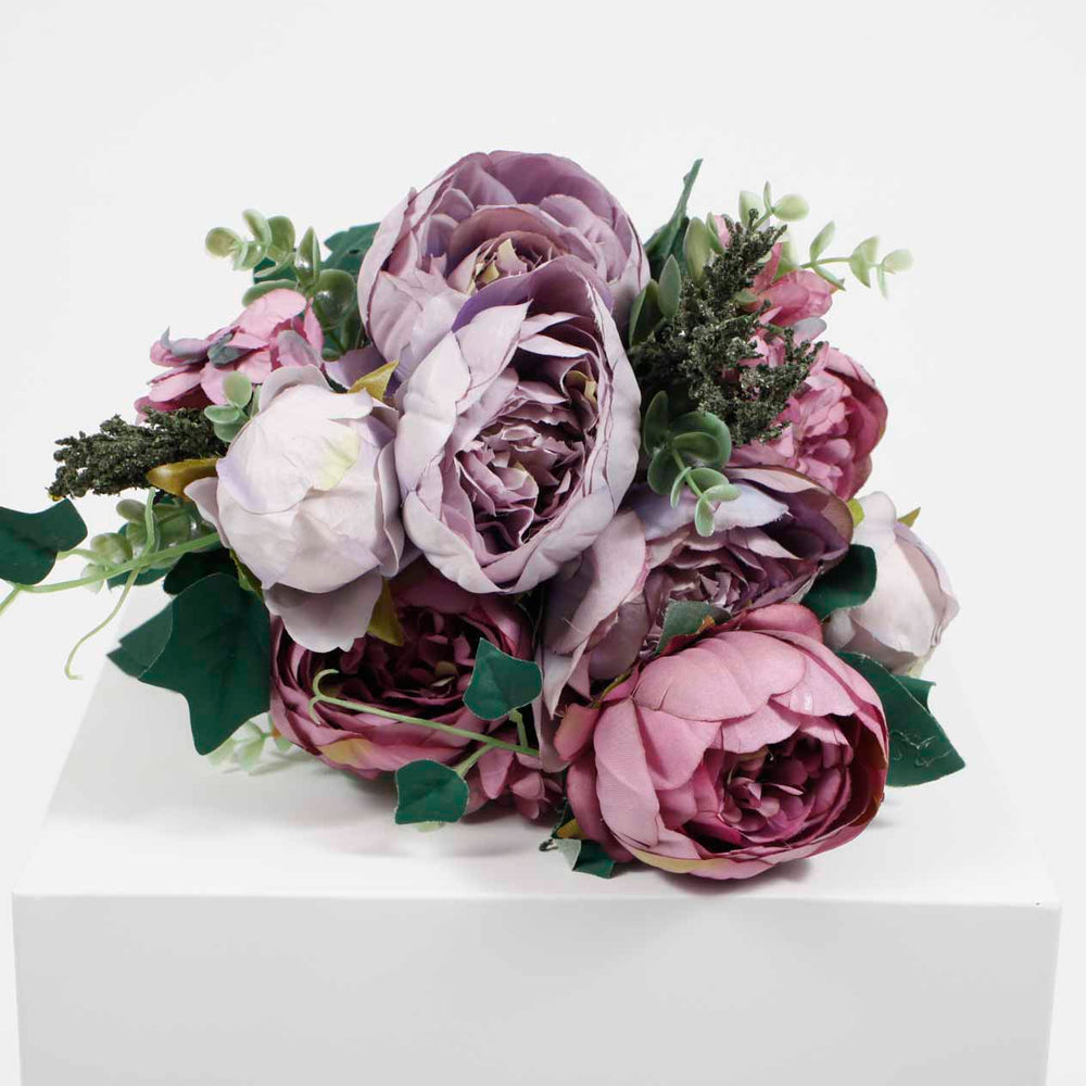 Close up view on bouquet of lavender & mauve roses fully open, half open and closed with green leafs, round pilea foliage and steams 