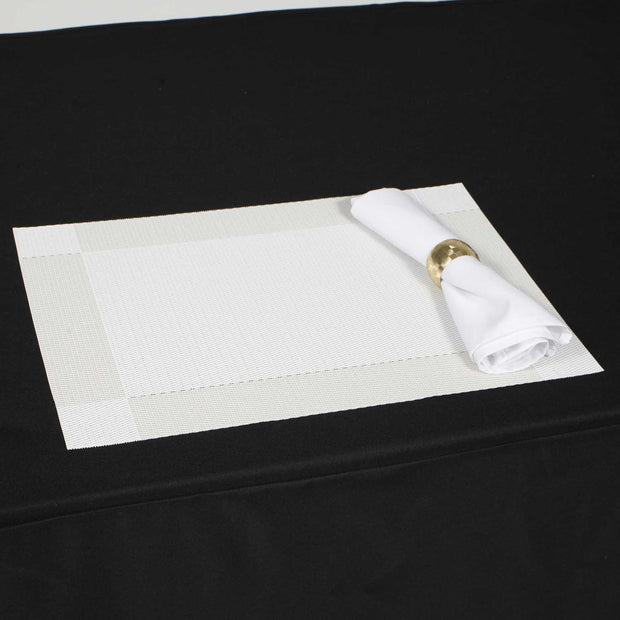White placemat with white napkin on black tablecloth 